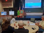 Mayor Callaway at Podium of Student Contest Luncheon, Baker family & Mayor Endicott viewing winning presentation